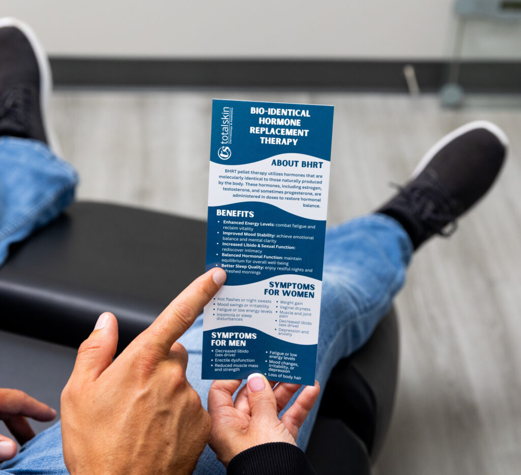 A provider holds a pamphlet on TRT in Grand Forks, while a patient at Total Skin points to some of the benefits he can expect to experience when beginning treatment.