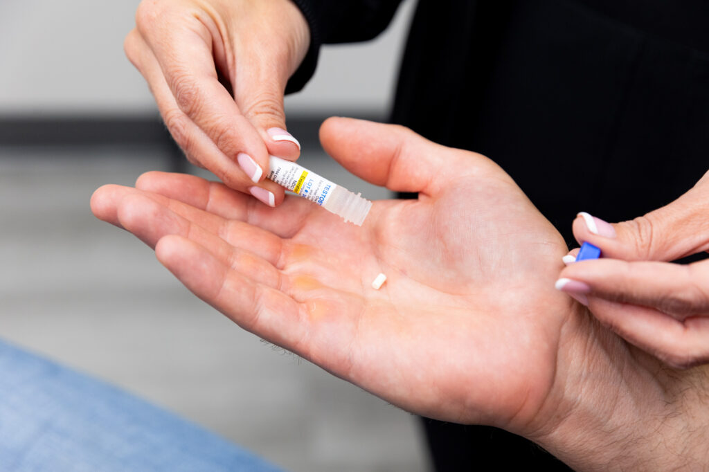 A provider at Total Skin demonstrates the size of the pellets used for TRT in Grand Forks. The pellet sits in the center of a patient's hand, and is as small as a grain of rice.