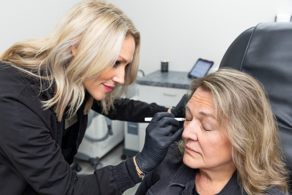 A Botox in Fargo provider, carefully marking injection zones on a patient about to have a treatment.
